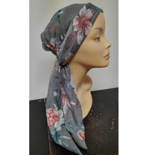 Lenço de cabeça cinzento com flores brancas e vermelhas, com as pontas soltas nas costas