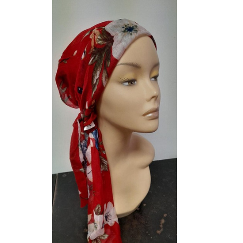 Lenço de cabeça vermelho com estampado de flores, atado numa cabeça de manequim