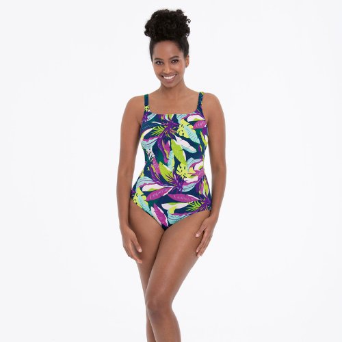 Mulher com fato de banho inteiro de estampado tropical em verde, rosa e roxo sobre fundo escuro