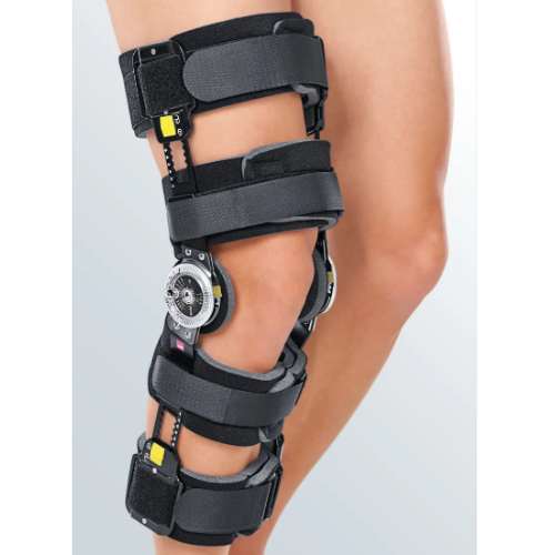 Joelheira articulada preta vestida numa perna, com mostrador graduado na lateral e tiras de velcro