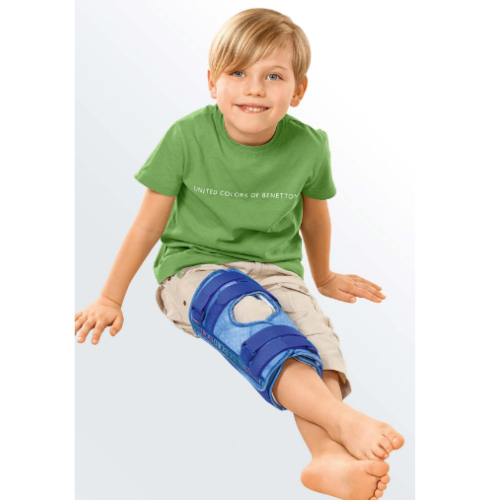 Menino sentado com a tala de imobilização do joelho Classic Kidz azul colocada na perna
